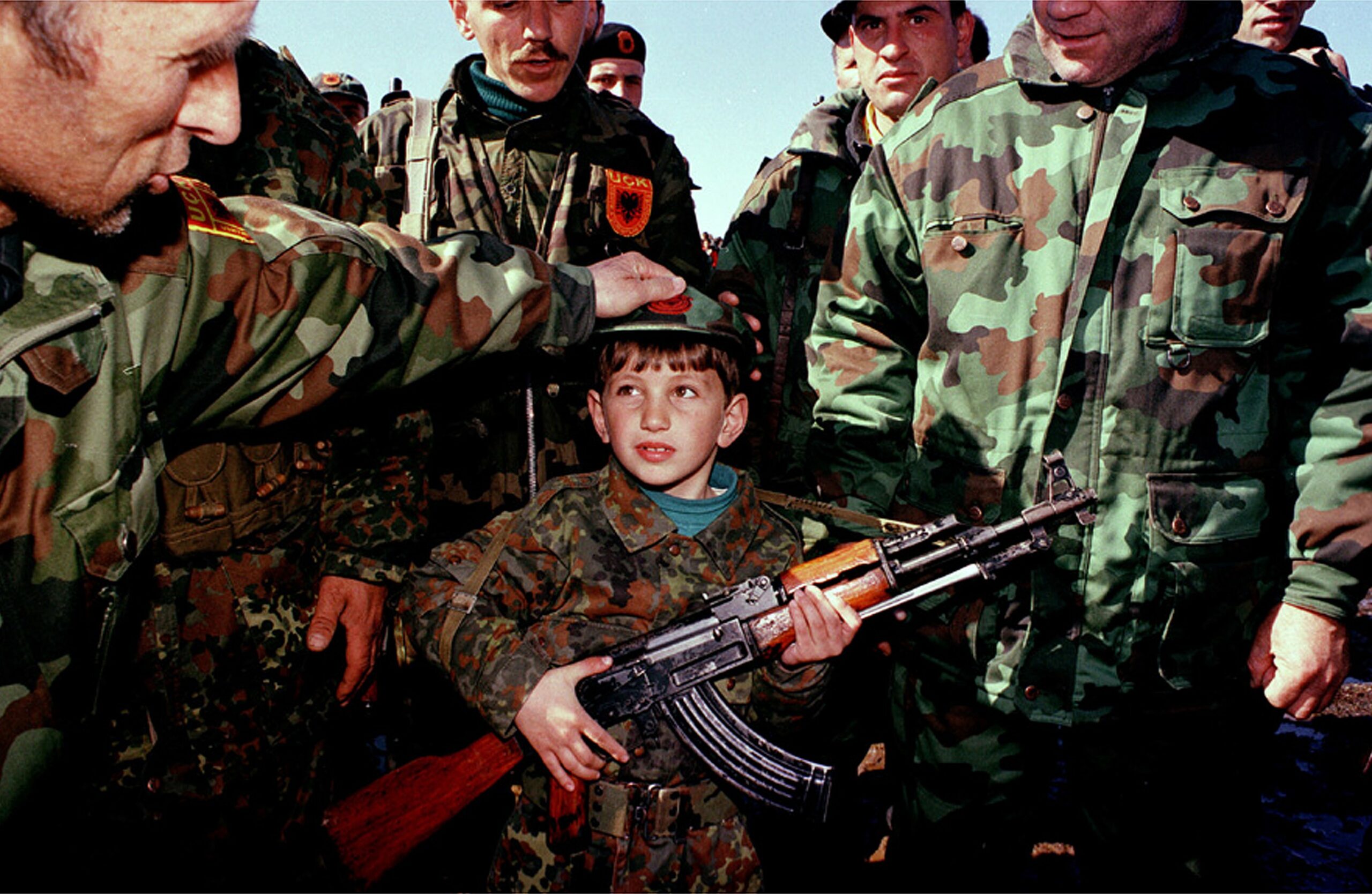 Военнослужащие Армии освобождения Косово и одетый в форму АОК ребенок с авт...